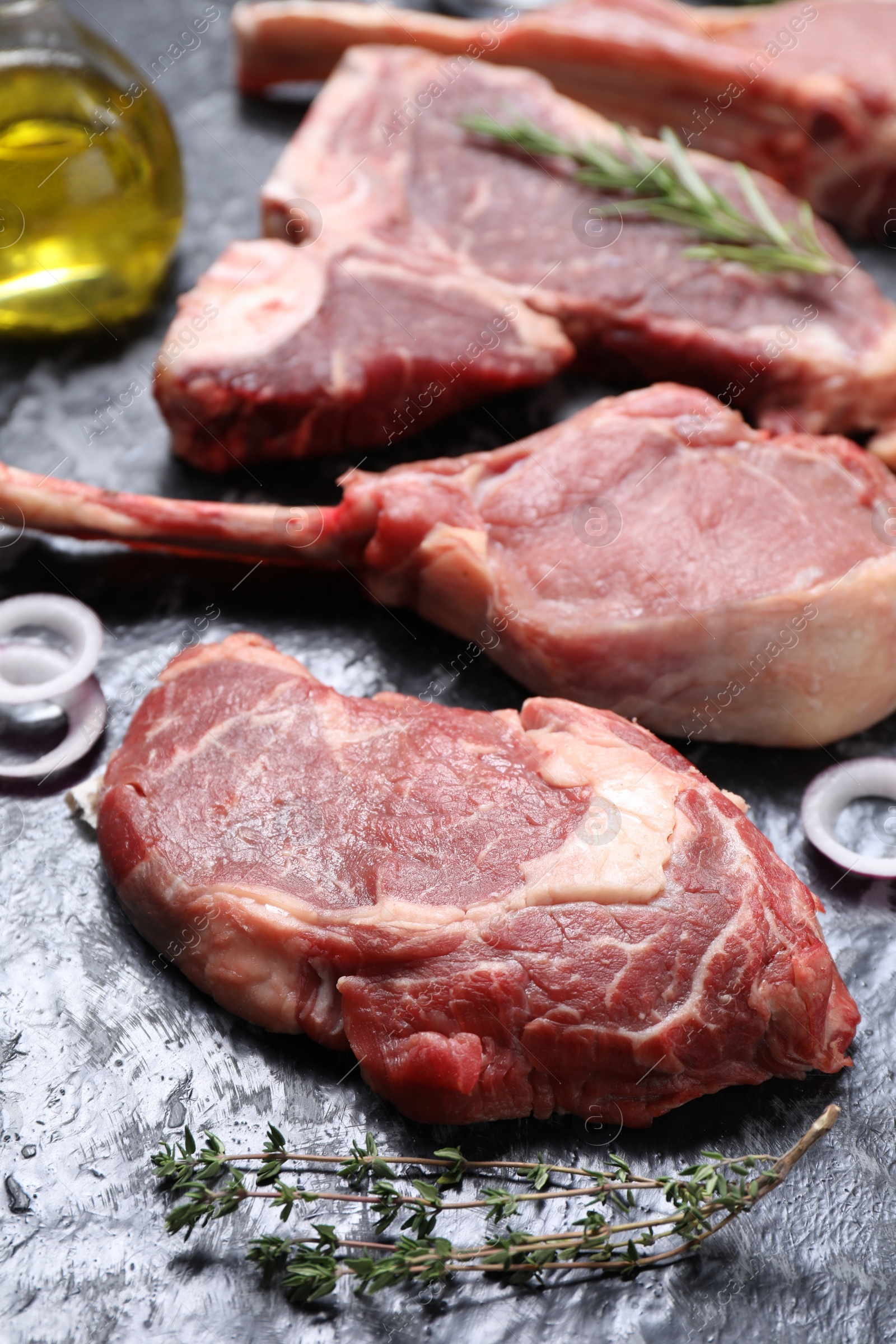 Photo of Fresh raw beef cuts and different spices on grey textured table