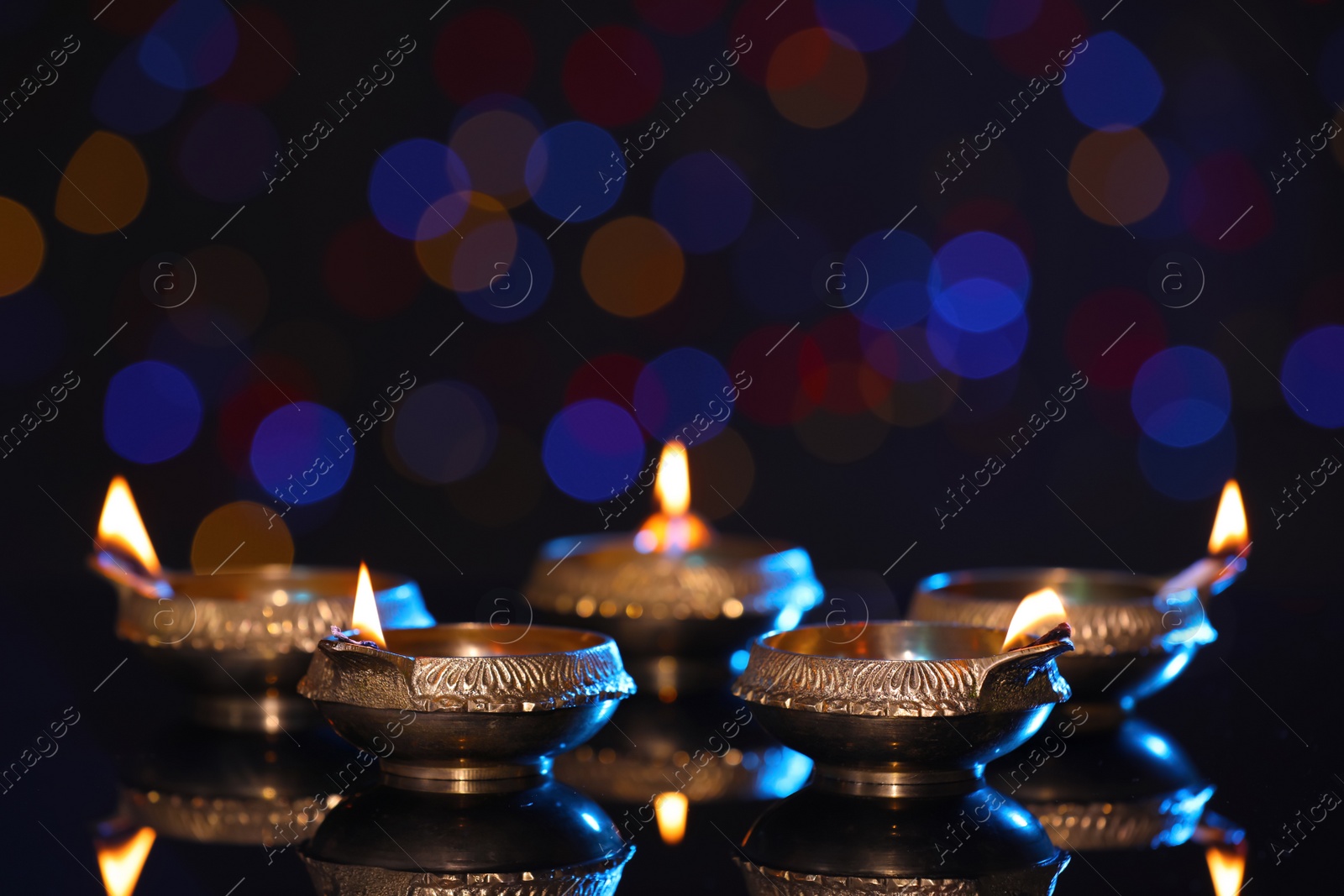 Photo of Many lit diyas on dark background with blurred lights, space for text. Diwali lamps