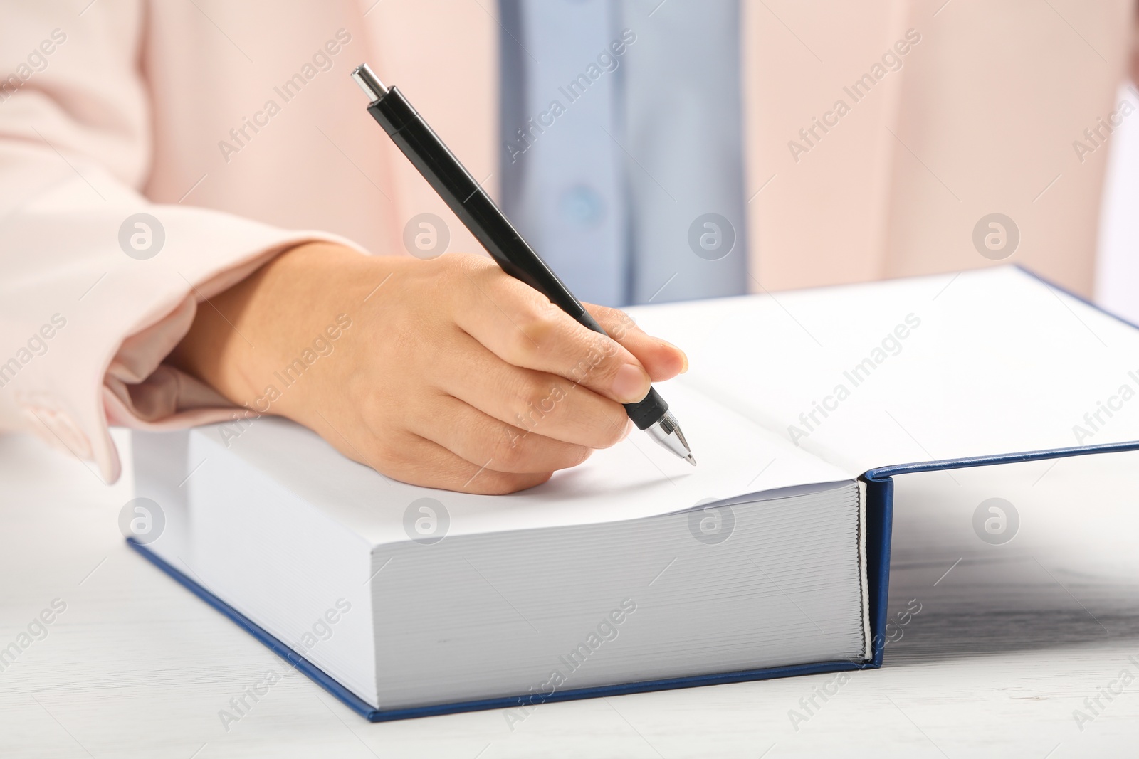 Photo of Writer signing autograph in book at table, closeup