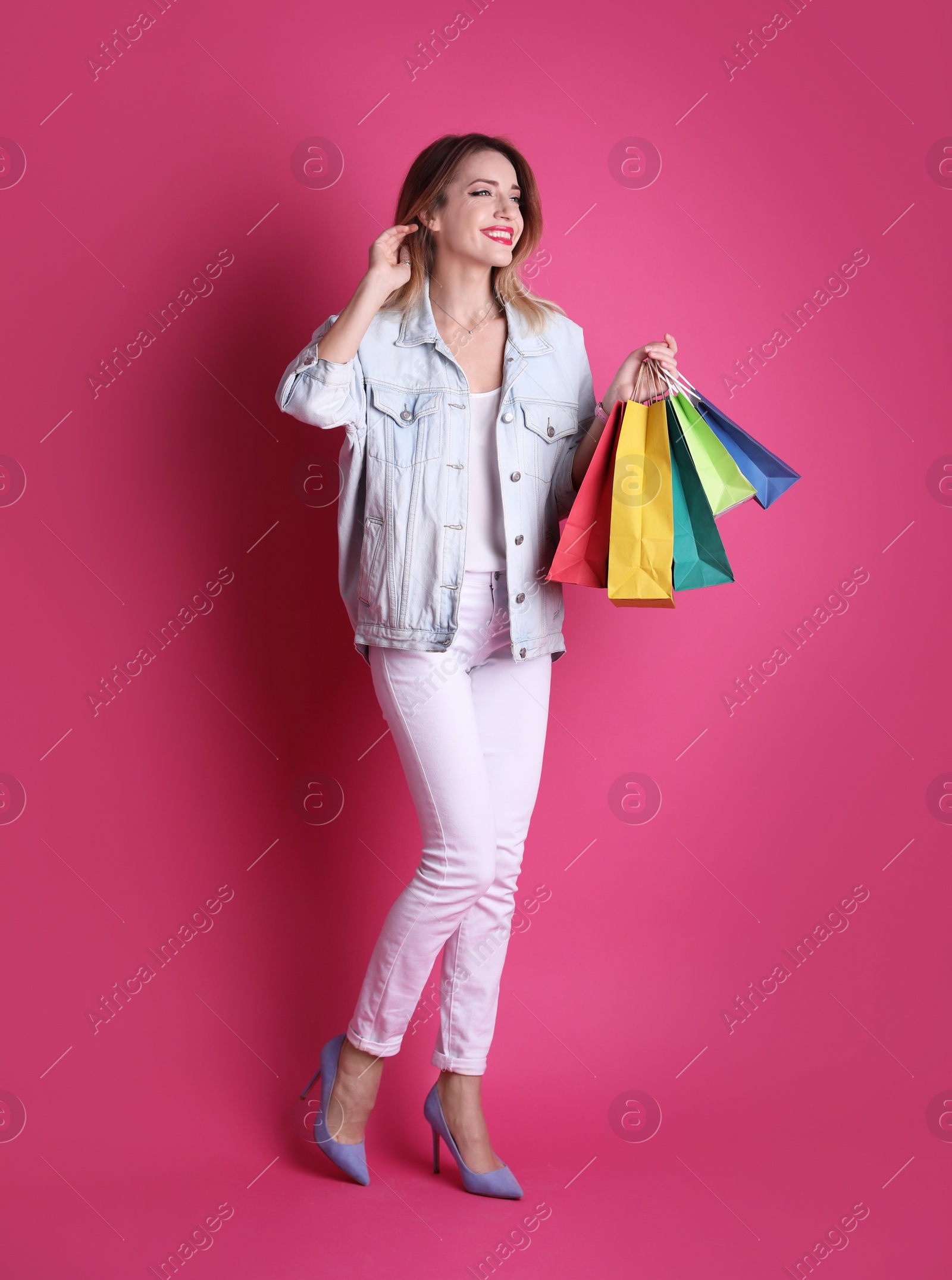 Photo of Beautiful young woman with shopping bags on color background