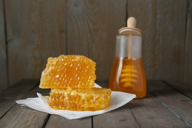 Photo of Natural honeycombs and honey on wooden table, selective focus. Space for text