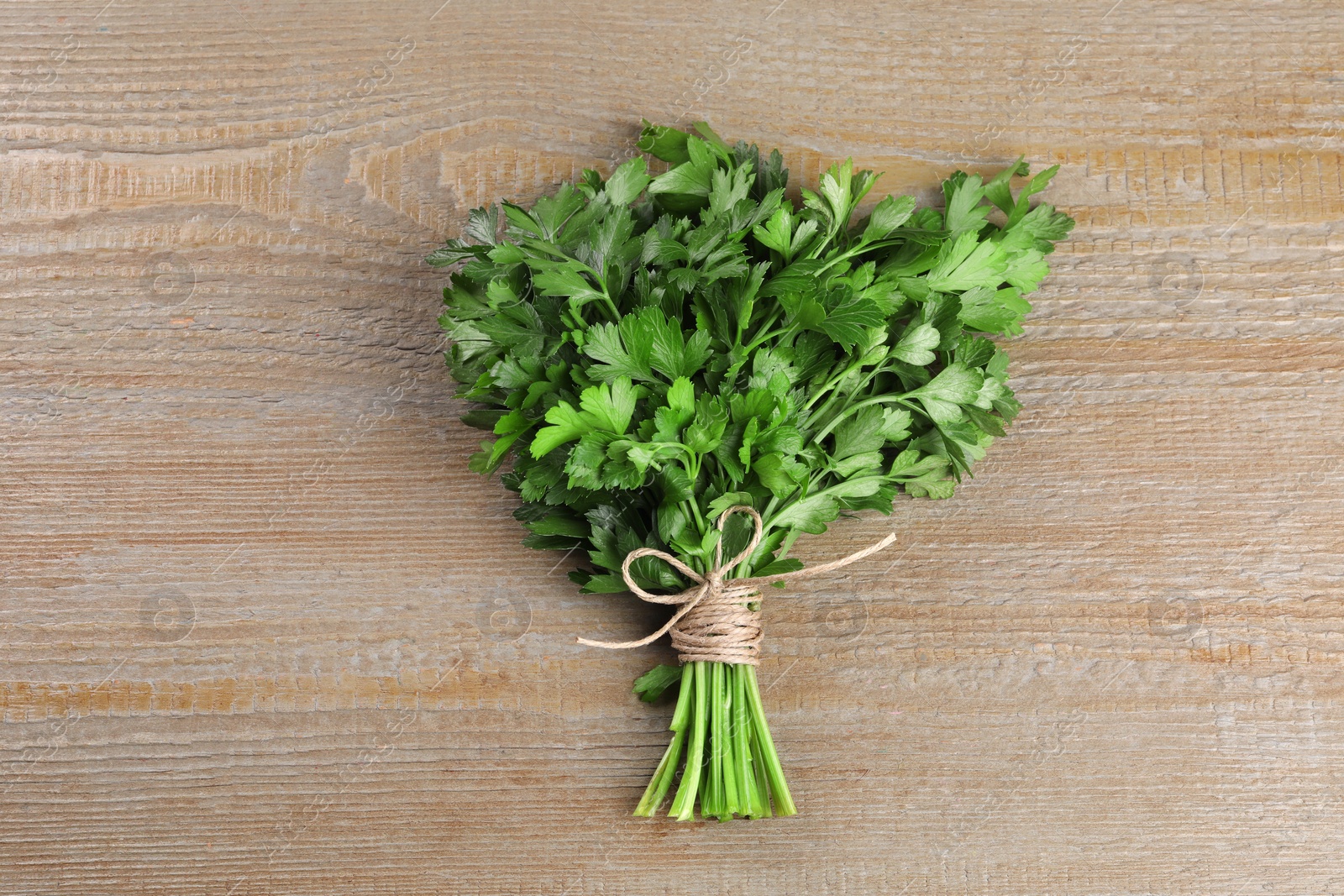 Photo of Bunch of fresh green parsley leaves on light wooden table, top view