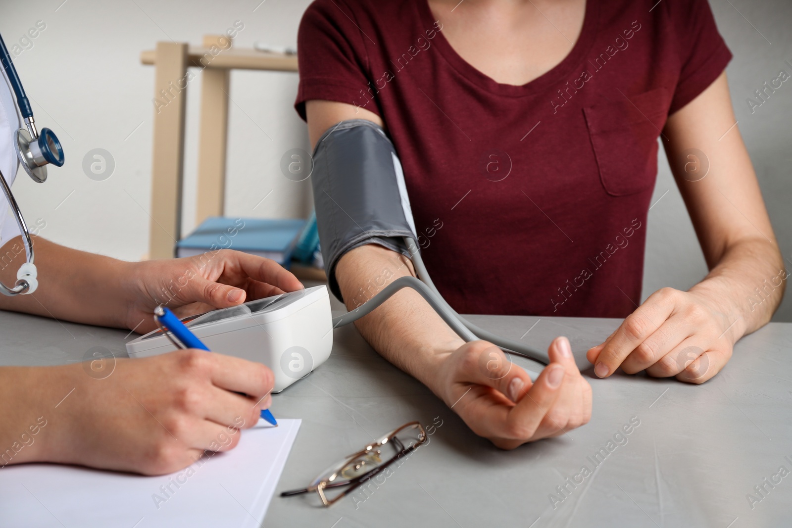 Photo of Doctor measuring blood pressure of woman in clinic, closeup. Medical service