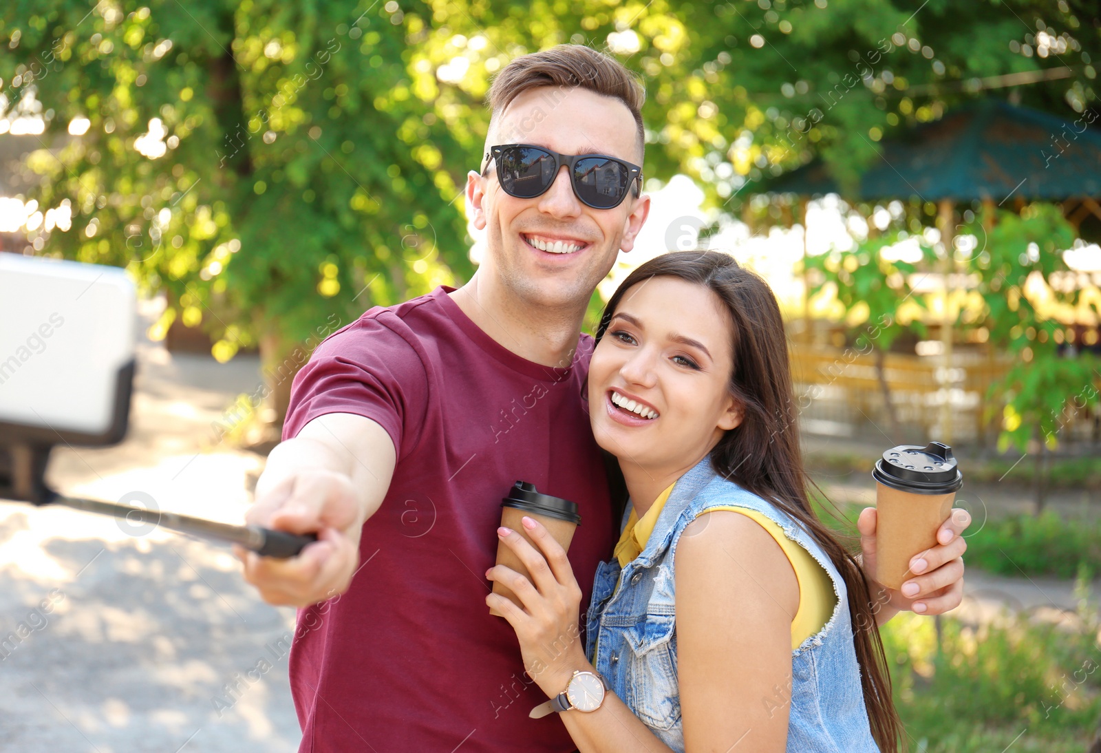 Photo of Young couple taking selfie with monopod outdoors