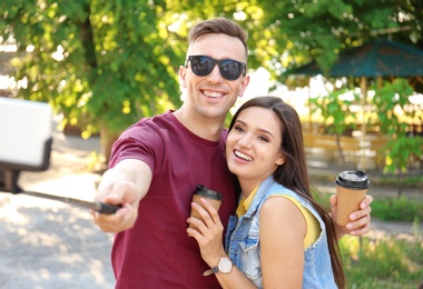 Young couple taking selfie with monopod outdoors