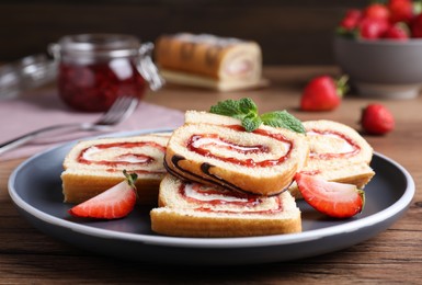 Photo of Tasty cake roll with strawberry jam and cream on wooden table, closeup