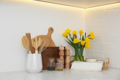 Wooden kitchenware and narcissus flowers on counter indoors
