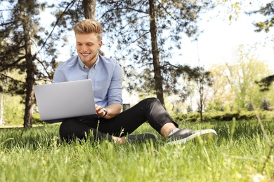 Image of Young man working on laptop in park