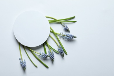 Photo of Beautiful spring muscari flowers and card on light background, flat lay. Space for text