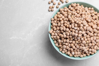 Photo of Chickpeas in bowl on light grey table, top view. Space for text