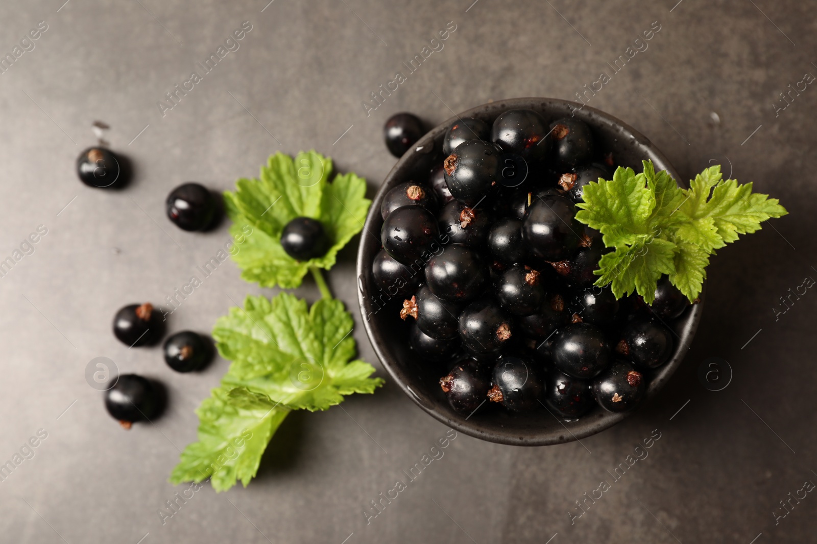 Photo of Ripe blackcurrants and leaves on grey background, flat lay