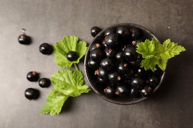 Ripe blackcurrants and leaves on grey background, flat lay