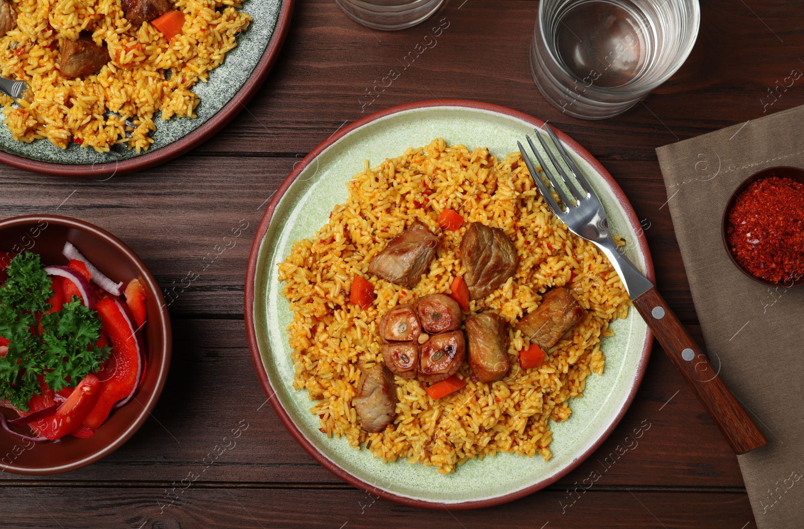 Photo of Flat lay composition with plate of rice pilaf and meat on wooden background