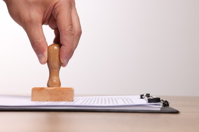 Man stamping documents at wooden table, closeup. Space for text