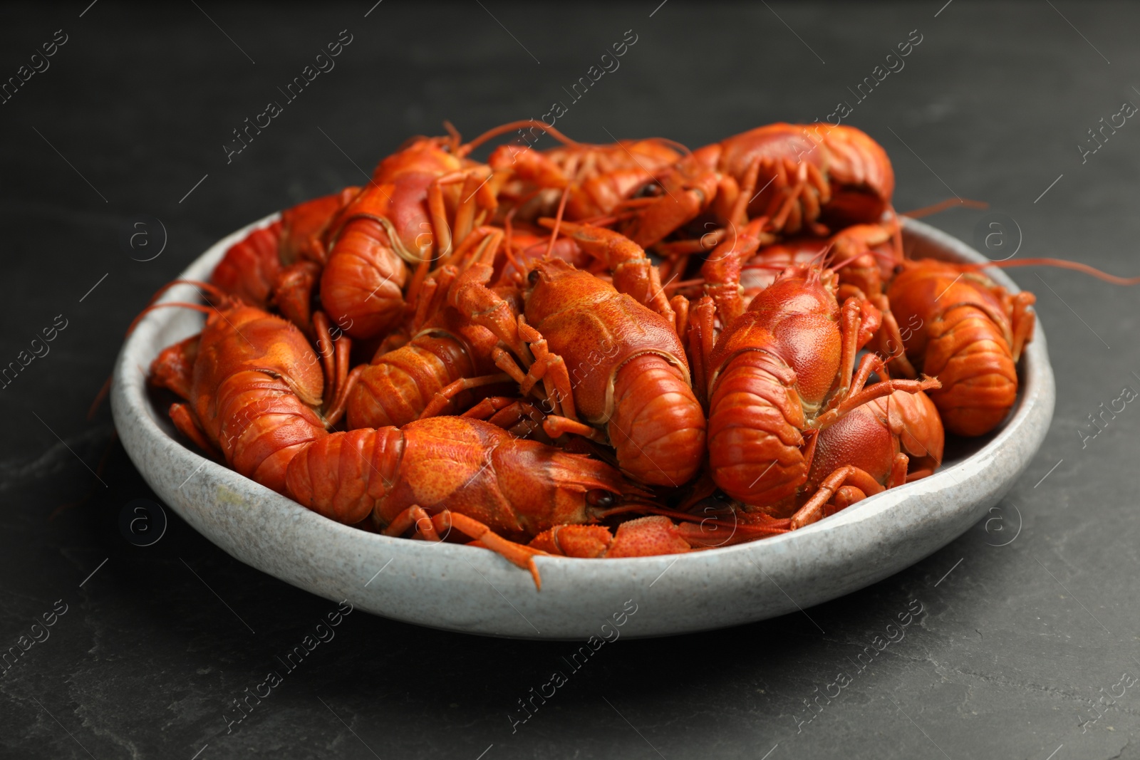 Photo of Delicious boiled crayfishes in plate on black table