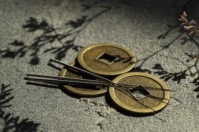 Acupuncture needles and Chinese coins on stone surface