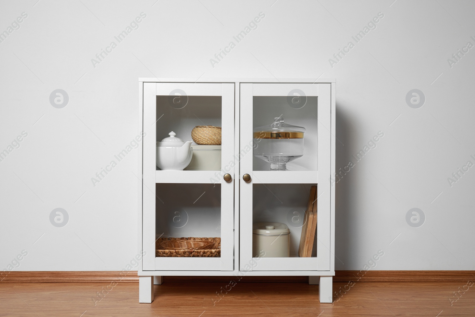 Photo of Wooden cabinet with kitchenware near white wall