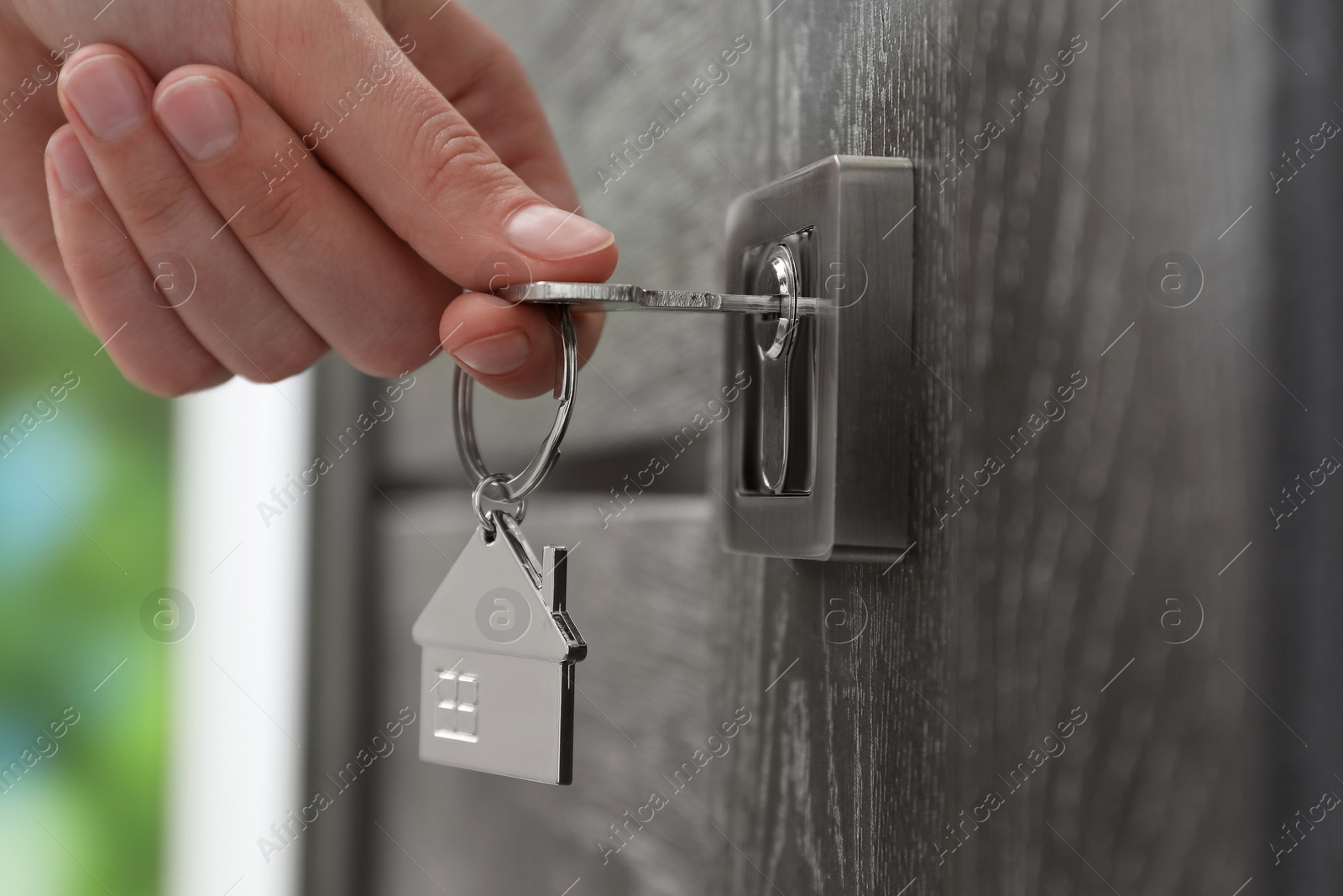 Photo of Woman unlocking door with key outdoors, closeup