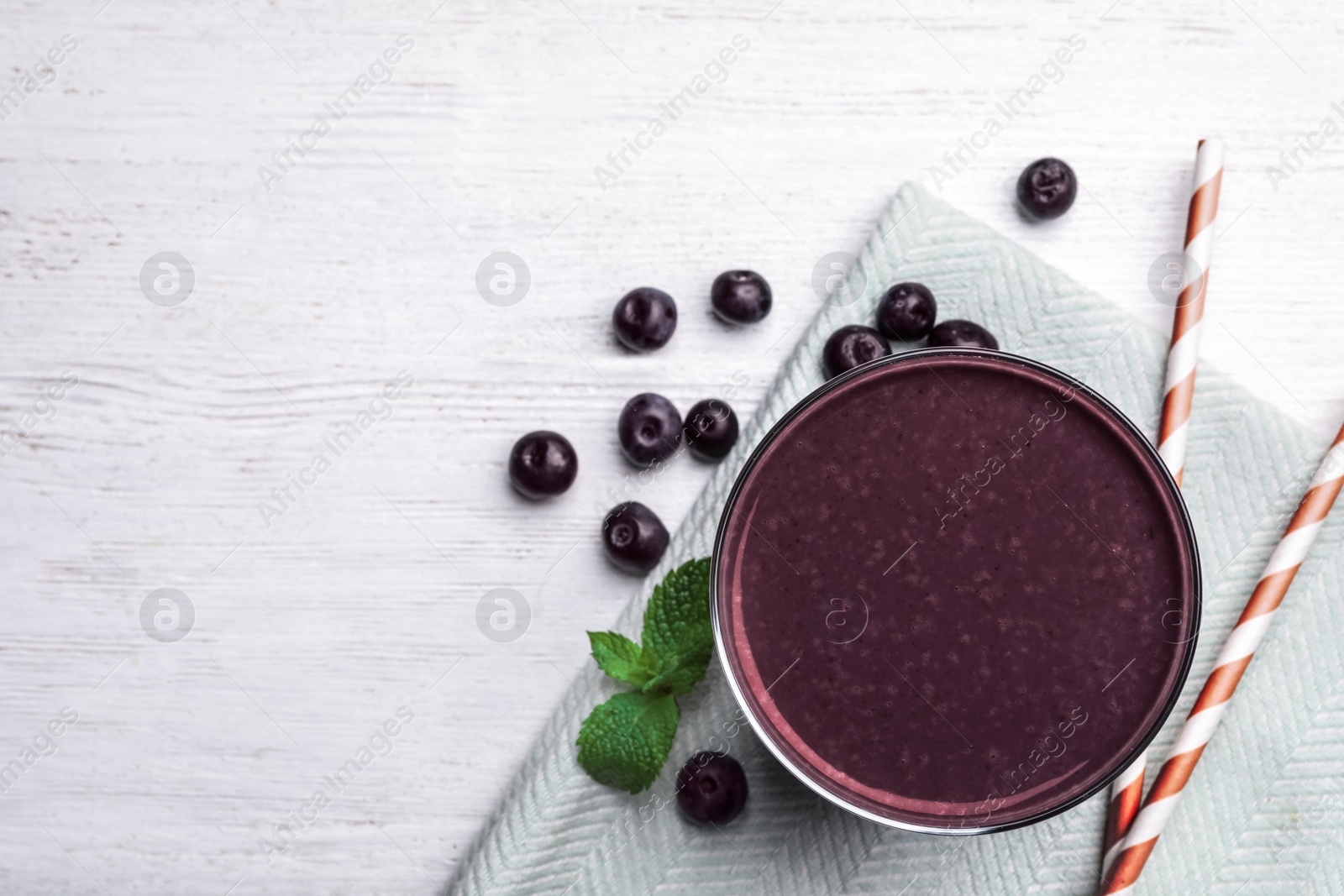 Photo of Fresh acai drink and berries on white wooden table, flat lay. Space for text