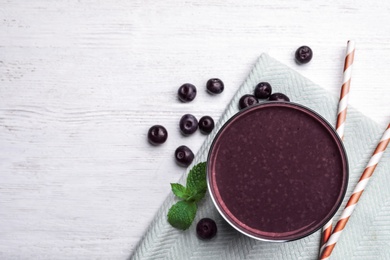 Fresh acai drink and berries on white wooden table, flat lay. Space for text