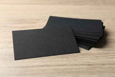 Blank black business cards on wooden table, closeup. Mockup for design