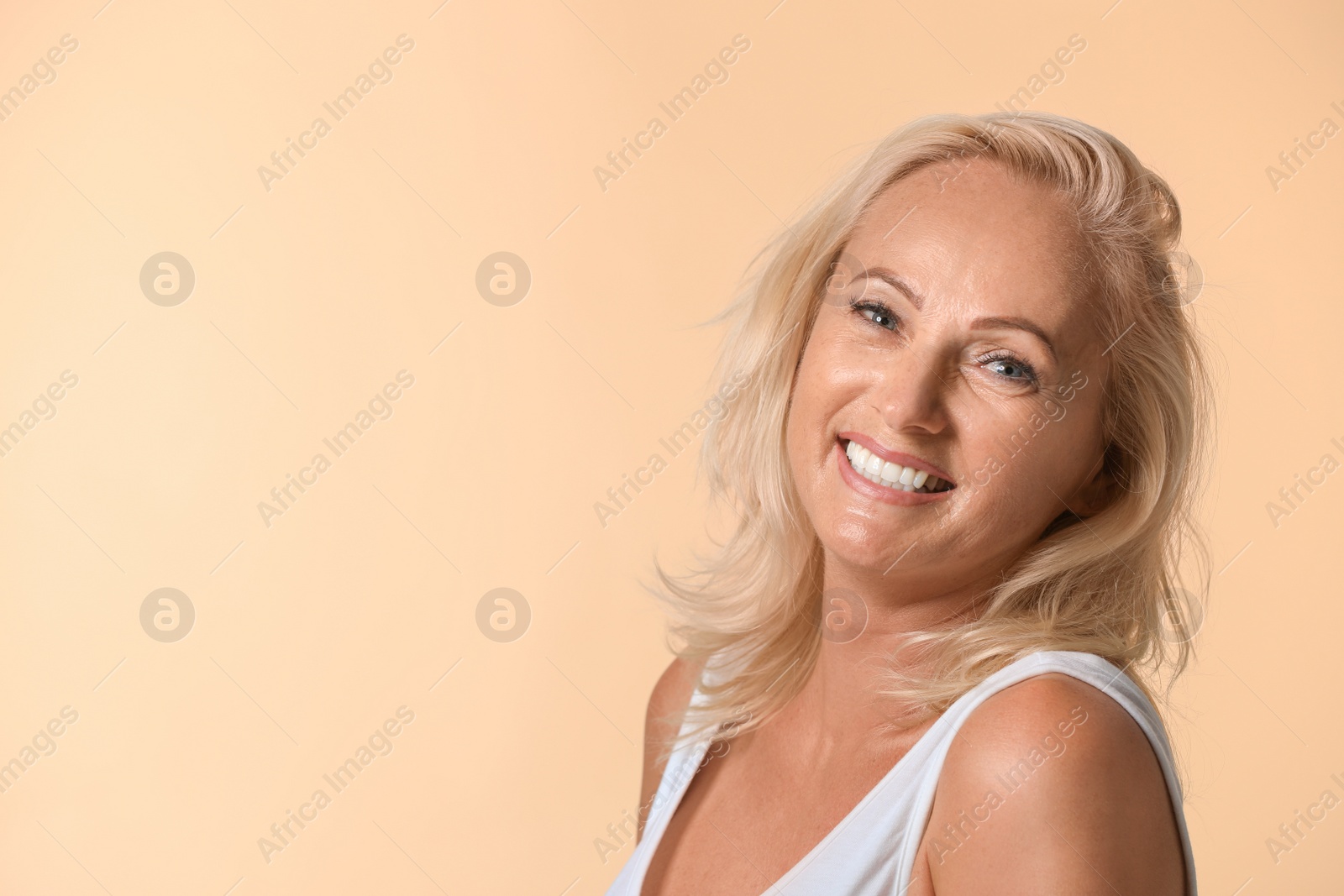 Photo of Portrait of beautiful mature woman with perfect skin on beige background. Space for text