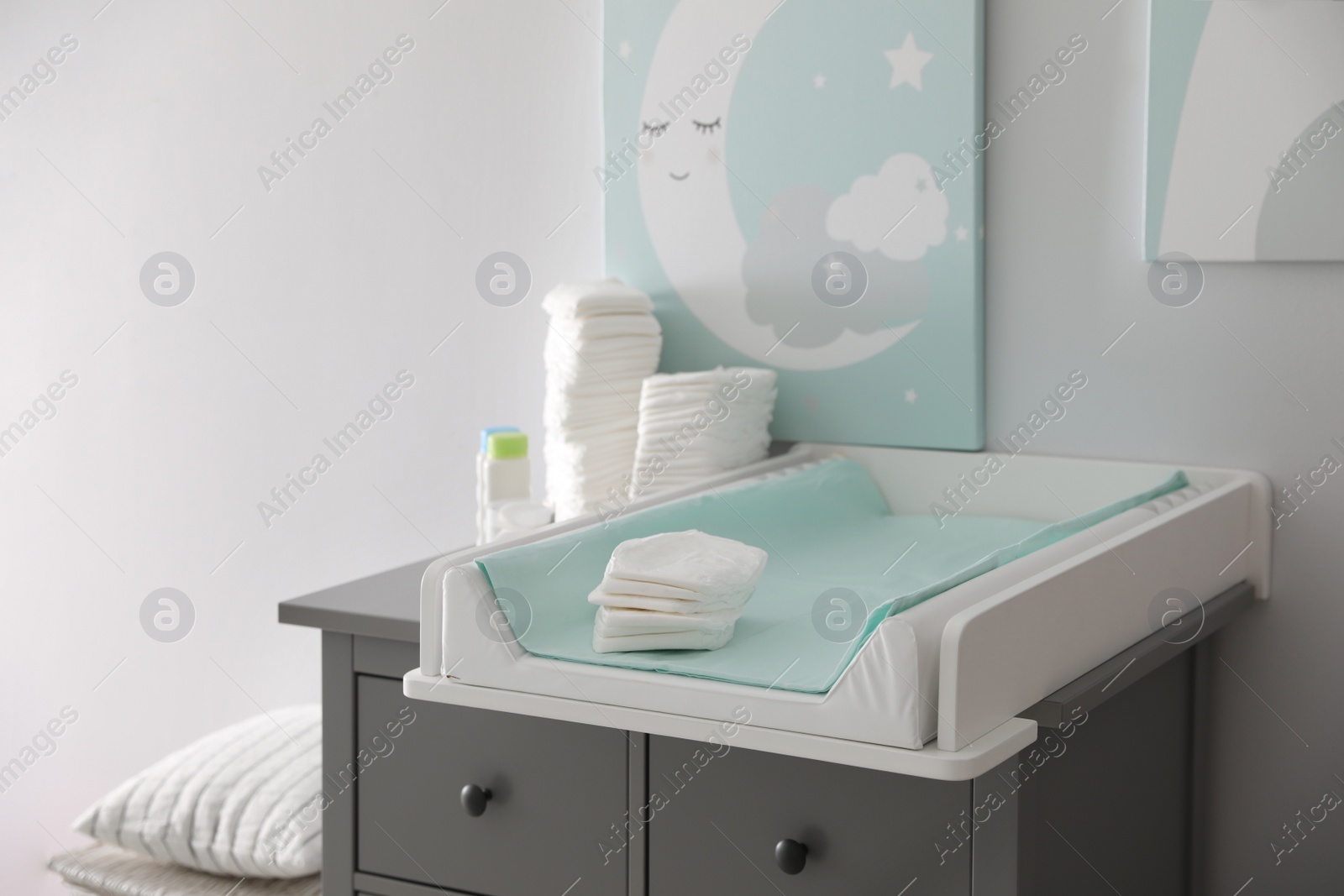 Photo of Chest of drawers with changing tray and pad in baby room. Interior design