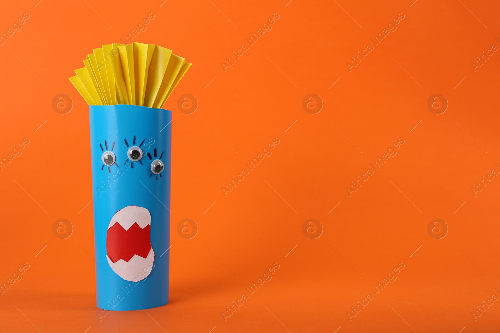 Photo of Funny blue monster on orange background, space for text. Halloween decoration