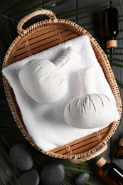 Flat lay composition with herbal massage bags and other spa products on grey wooden table