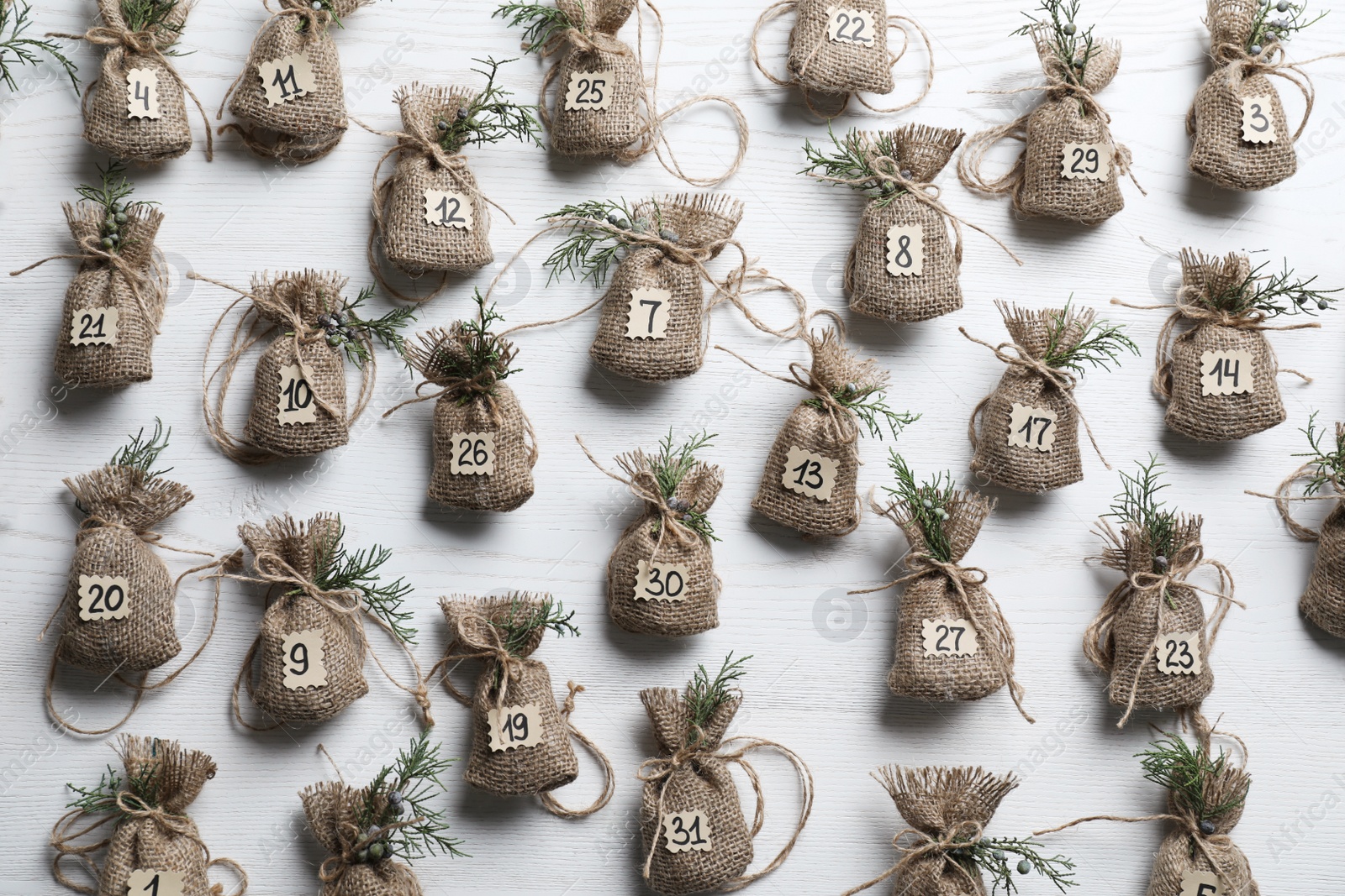 Photo of New Year advent calendar with gifts on white wooden background, flat lay