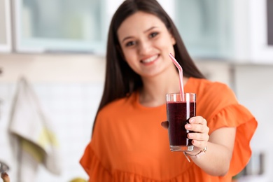 Photo of Young woman with glass of tasty healthy smoothie in kitchen