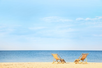 Sandy beach with empty wooden sunbeds on sunny day