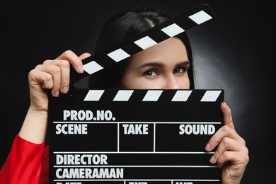 Photo of Actress with clapperboard on black background, closeup. Film industry