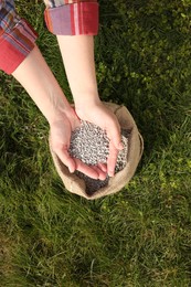 Photo of Woman with fertilizer on green grass outdoors, top view