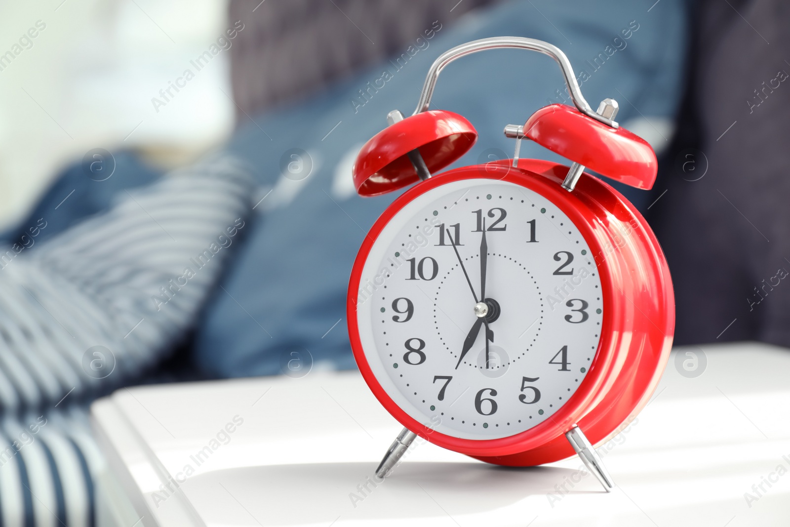 Photo of Analog alarm clock on table in bedroom. Time of day