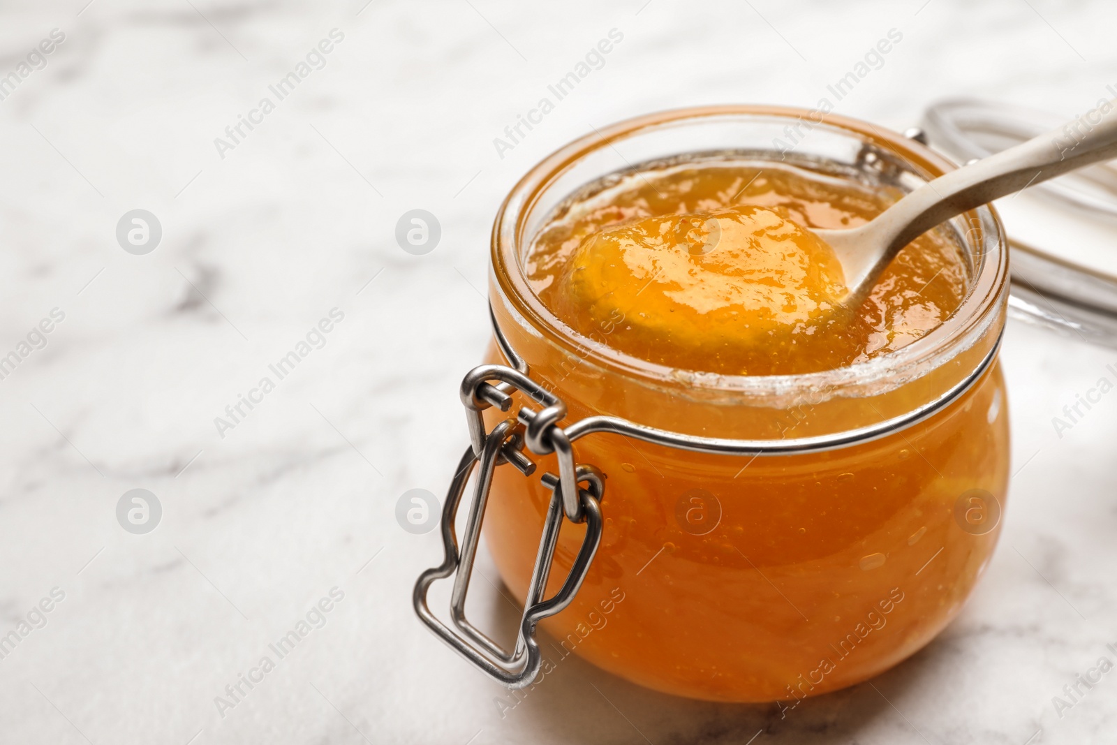Photo of Homemade delicious orange jam on marble table