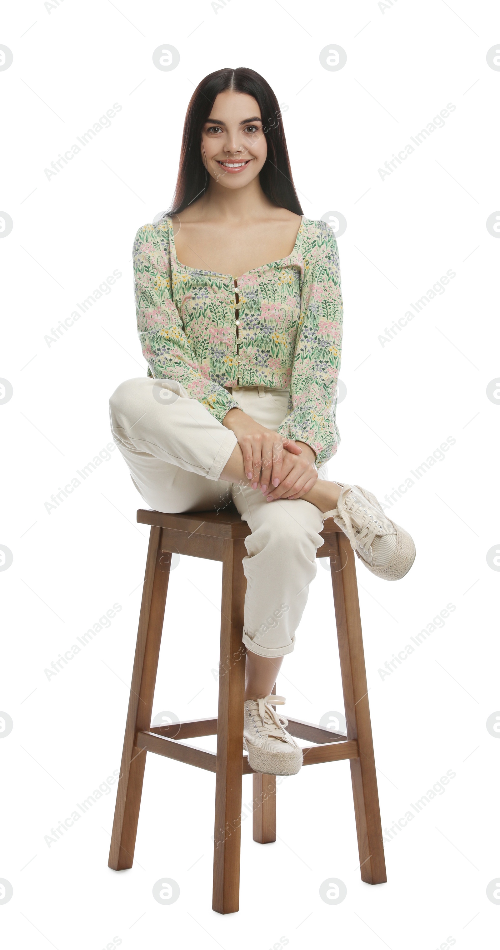 Photo of Beautiful young woman sitting on stool against white background