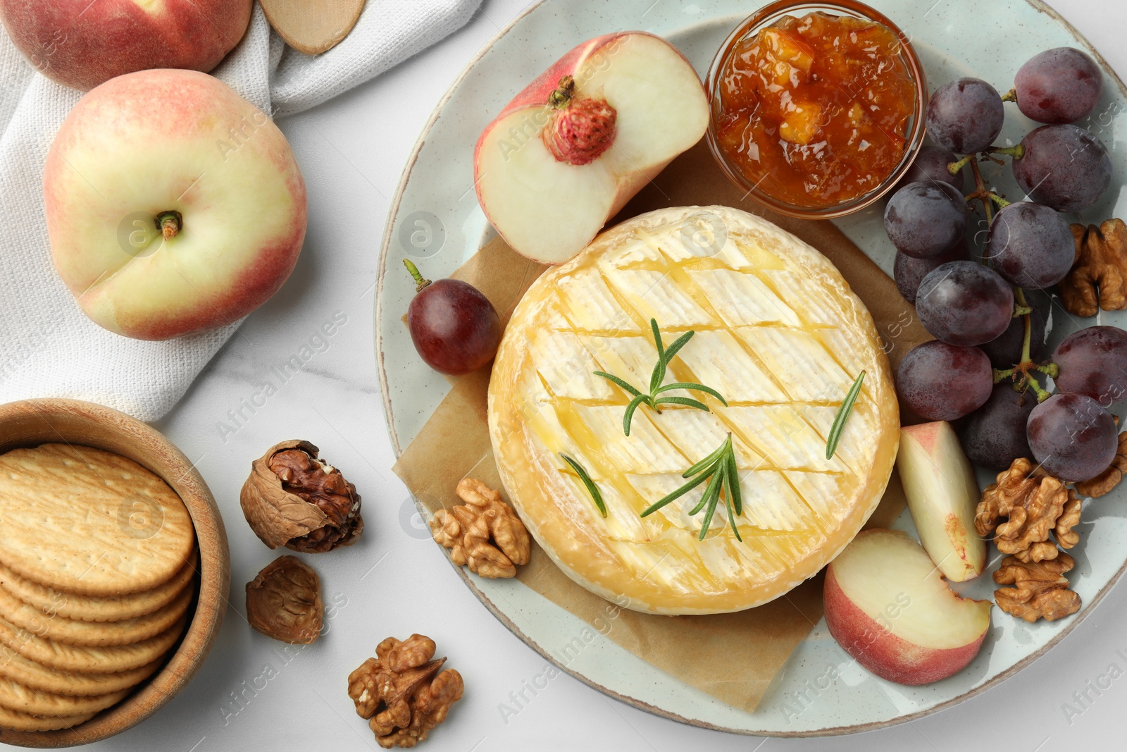 Photo of Tasty baked brie cheese served on white marble table, flat lay