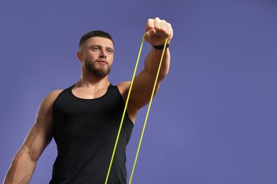 Muscular man exercising with elastic resistance band on purple background, low angle view. Space for text