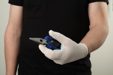 Man with needle nose pliers on light background, closeup