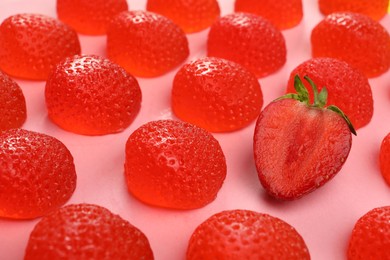 Photo of Delicious gummy candies and fresh strawberry on pink background, closeup