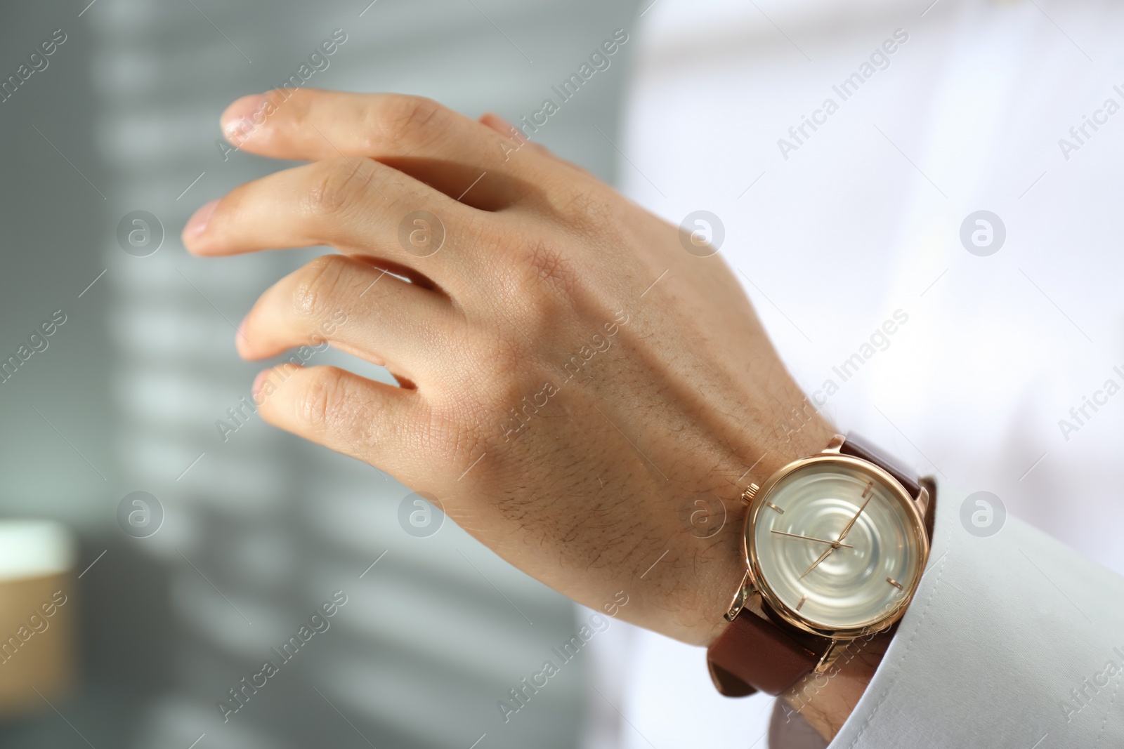 Photo of Man with luxury wrist watch on blurred background, closeup