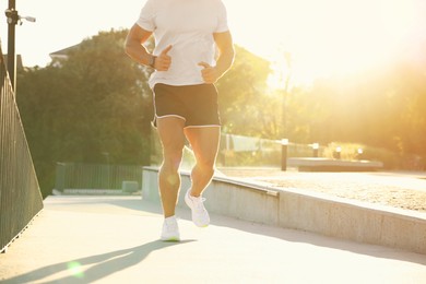 Man running outdoors on sunny day, closeup. Space for text