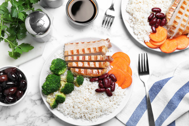 Photo of Delicious rice with beans and meat served on white marble table, flat lay