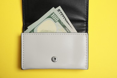 Stylish leather purse with dollar banknotes on yellow background, top view