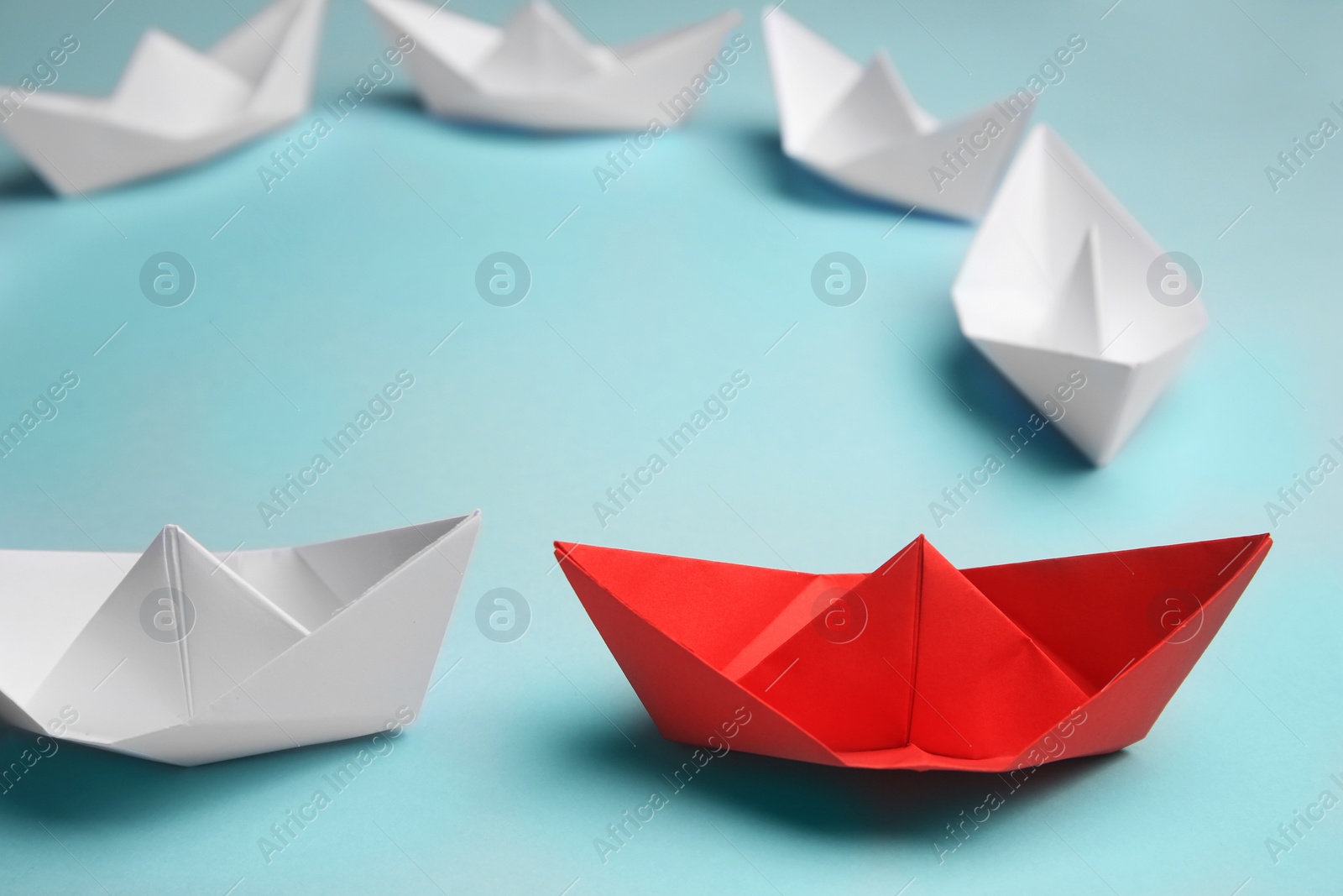 Photo of Group of paper boats following red one on light background. Leadership concept