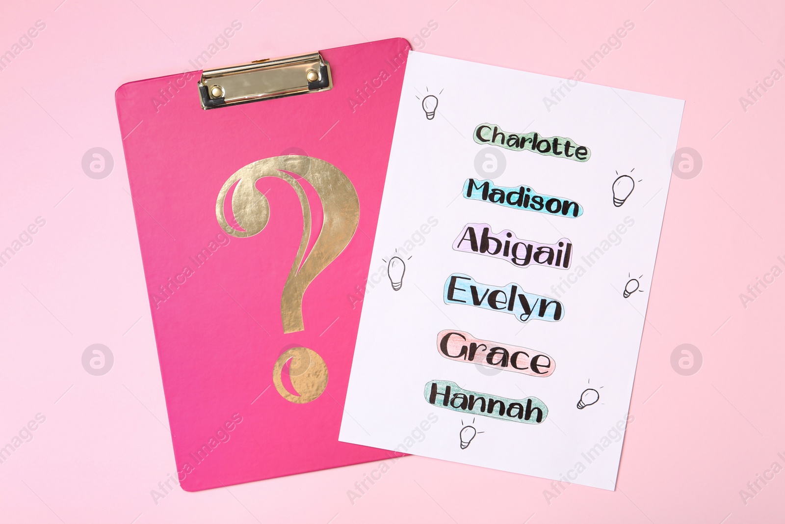 Photo of List of different baby names and clipboard on pink background, top view