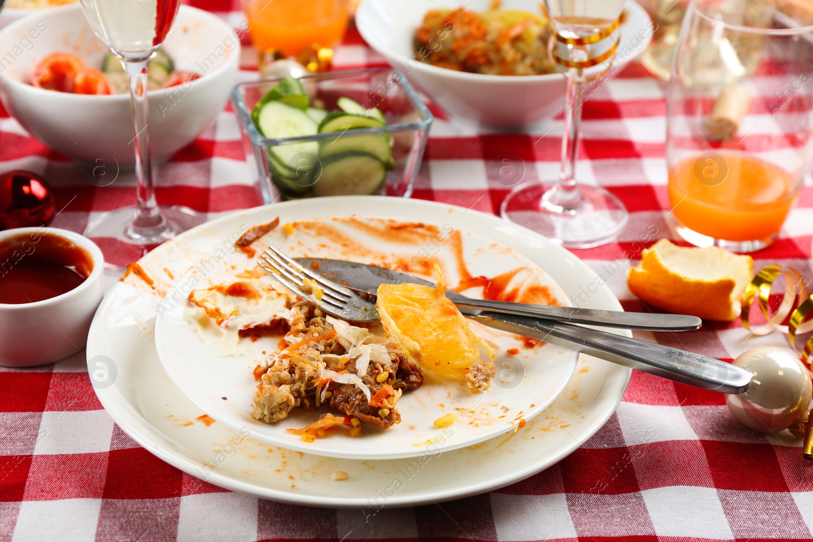 Photo of Food leftovers after party on table with checkered cloth, closeup