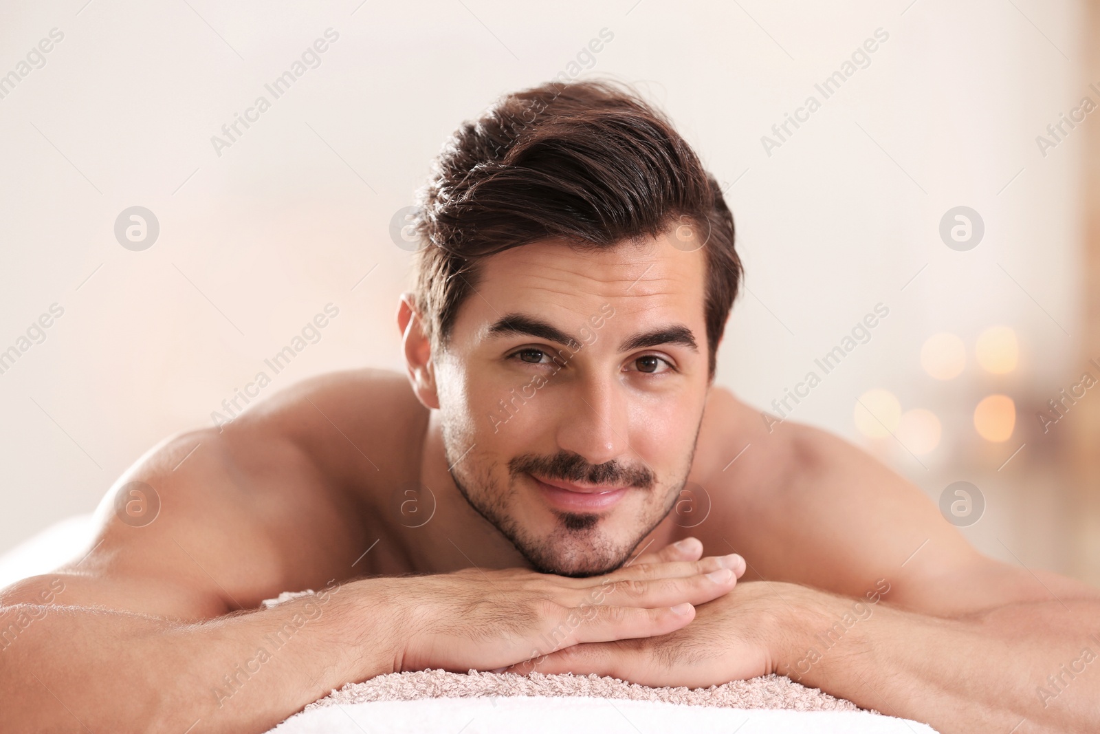 Photo of Handsome young man relaxing on massage table in spa salon