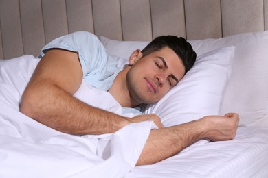 Photo of Man sleeping in comfortable bed with white linens